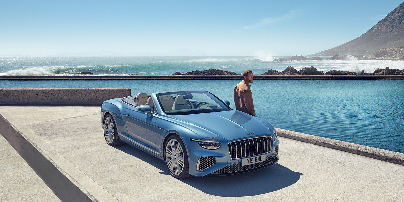 Bentley Hong Kong - DCH New Bentley Continental GTC Azure convertible front view in Light Windsor blue paint with 22 inch ten spoke wheels parked by the sea in the sunshine