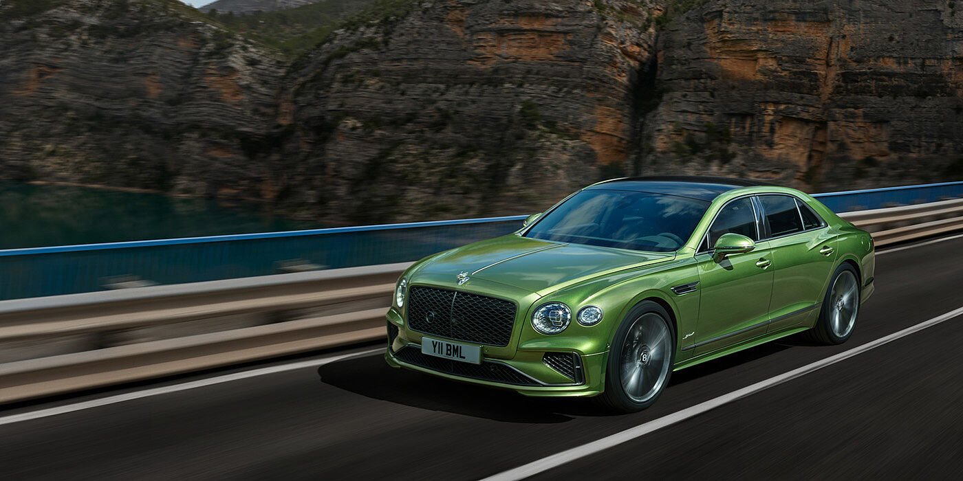 Bentley Hong Kong - DCH Bentley New Flying Spur Speed v8 hybrid sedan driving dynamically on a mountain road in Tourmaline Green paint