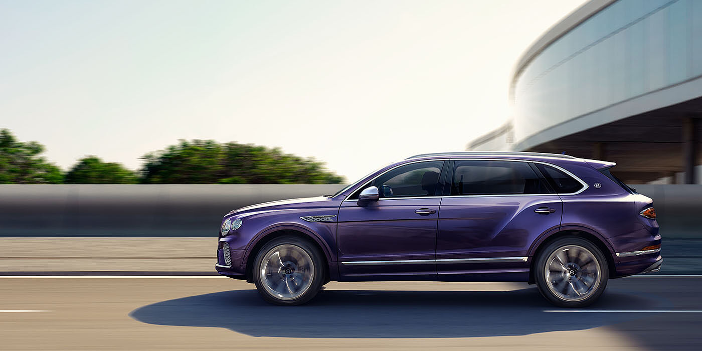 Bentley Hong Kong - DCH Bentley Bentayga Extended Wheelbase Mulliner luxury SUV profile in Tanzanite Purple paint, driving on an country road past trees.
