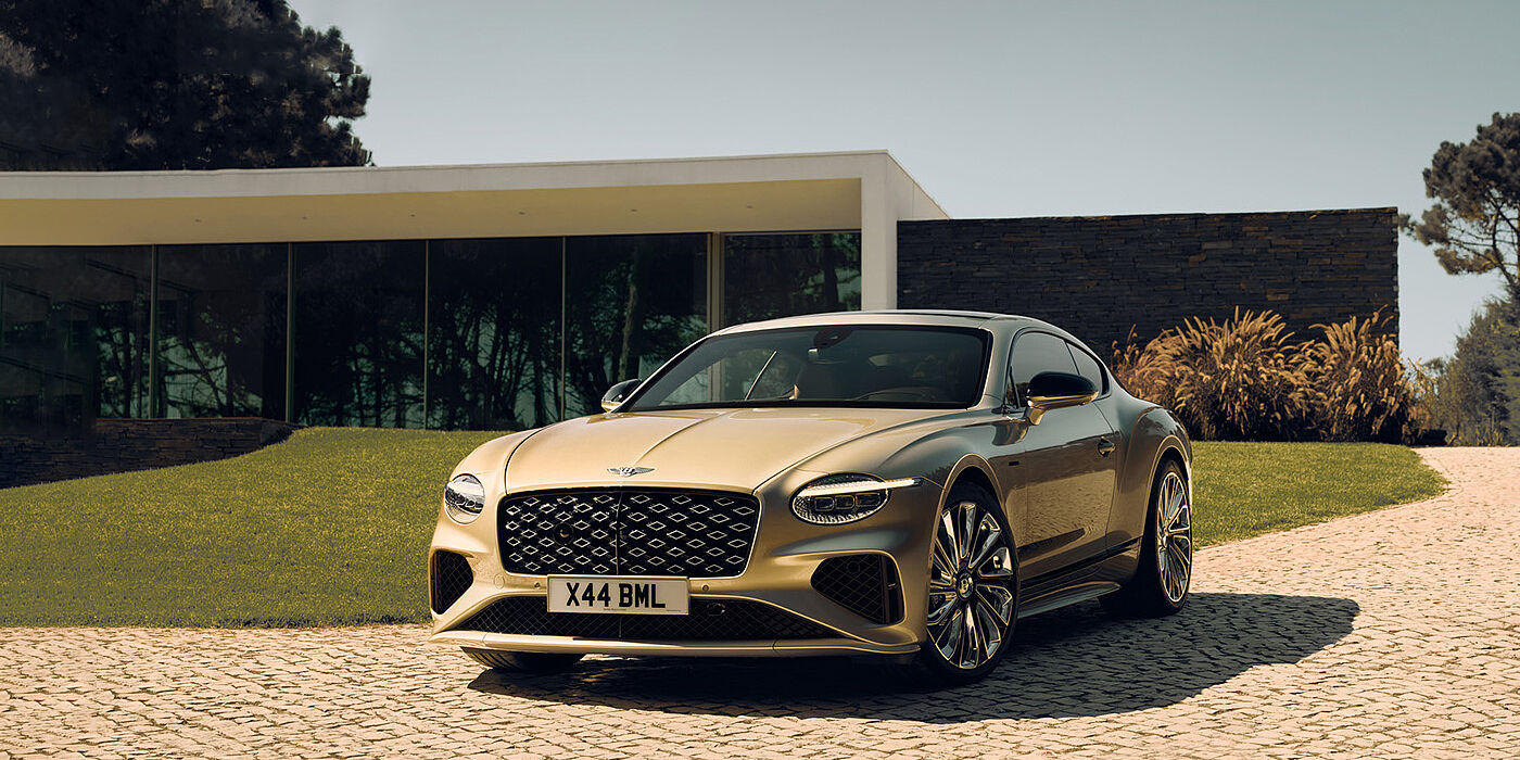 Bentley Hong Kong - DCH Bentley Continental GT Mulliner coupe front three quarters in Patina paint parked outside a glass fronted building with a grass lawn behind it
