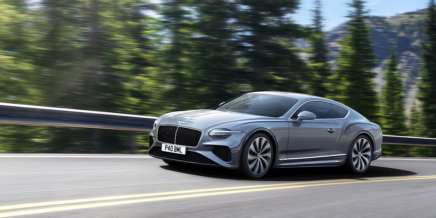 Bentley Hong Kong - DCH New Bentley Continental GT coupe in Silverlake paint and 22 inch ten-spoke wheels, driving dynamically on a tree-lined road in the sunshine