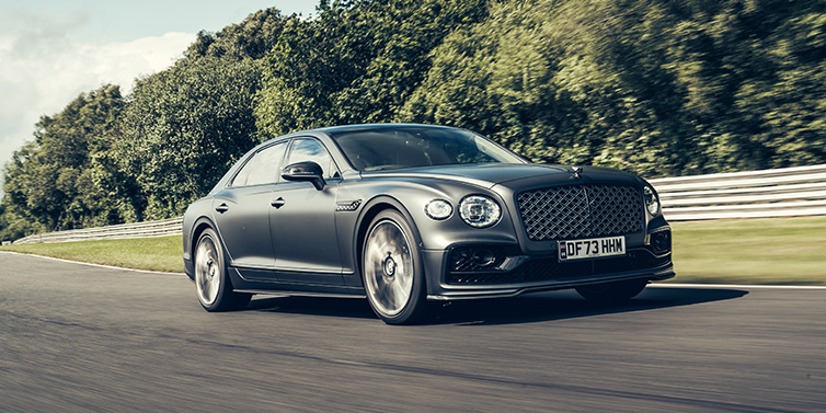 Bentley Hong Kong - DCH Bentley Flying Spur Mulliner sedan front three quarter in dark grey paint driving dynamically by some trees on a track 