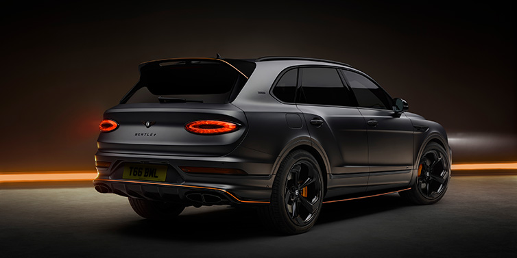 Bentley Hong Kong - DCH Bentley Bentayga S Black Edition SUV rear three quarter in Anthracite Satin paint against a dark red and yellow background
