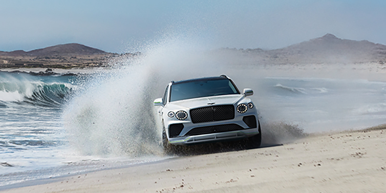Bentley Hong Kong - DCH Bentley Bentayga Speed SUV facing front in Snow Quarts Pearlescent white paint driving dynamically on beach
