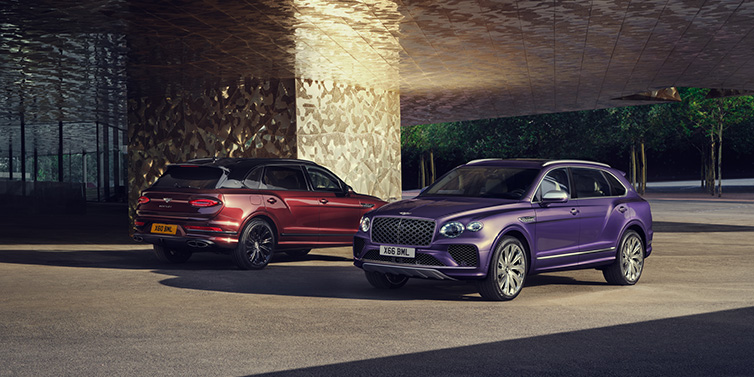 Bentley Hong Kong - DCH A duo of Bentley Bentayga Extended Wheelbase Mulliner SUVs parked in a city environment, with Tanzanite Purple and Cricket Ball red exterior paint